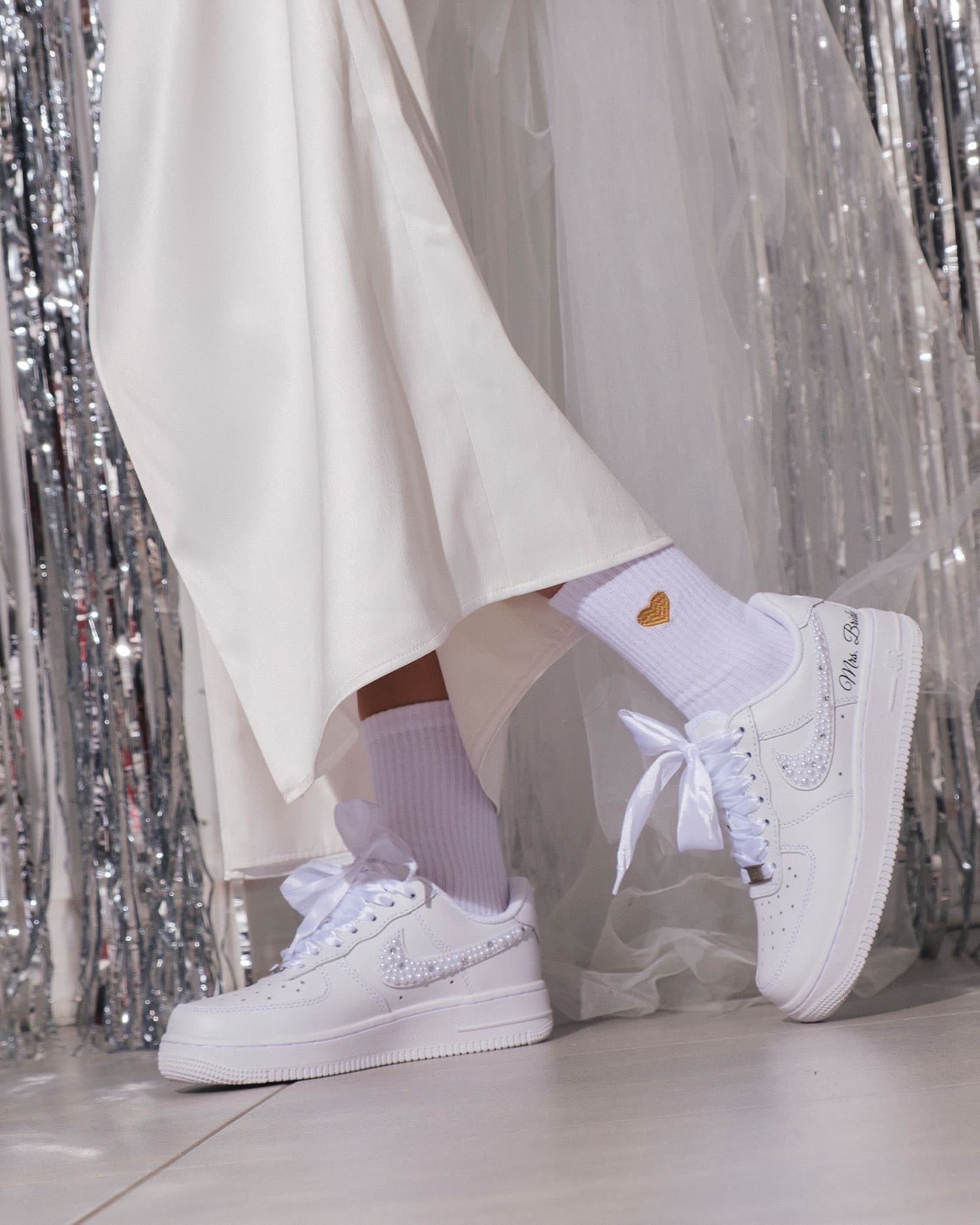 Close-up of custom white Air Force 1 wedding sneakers with pearl details and satin laces. Personalized bridal shoes for a stylish and comfortable wedding day.
