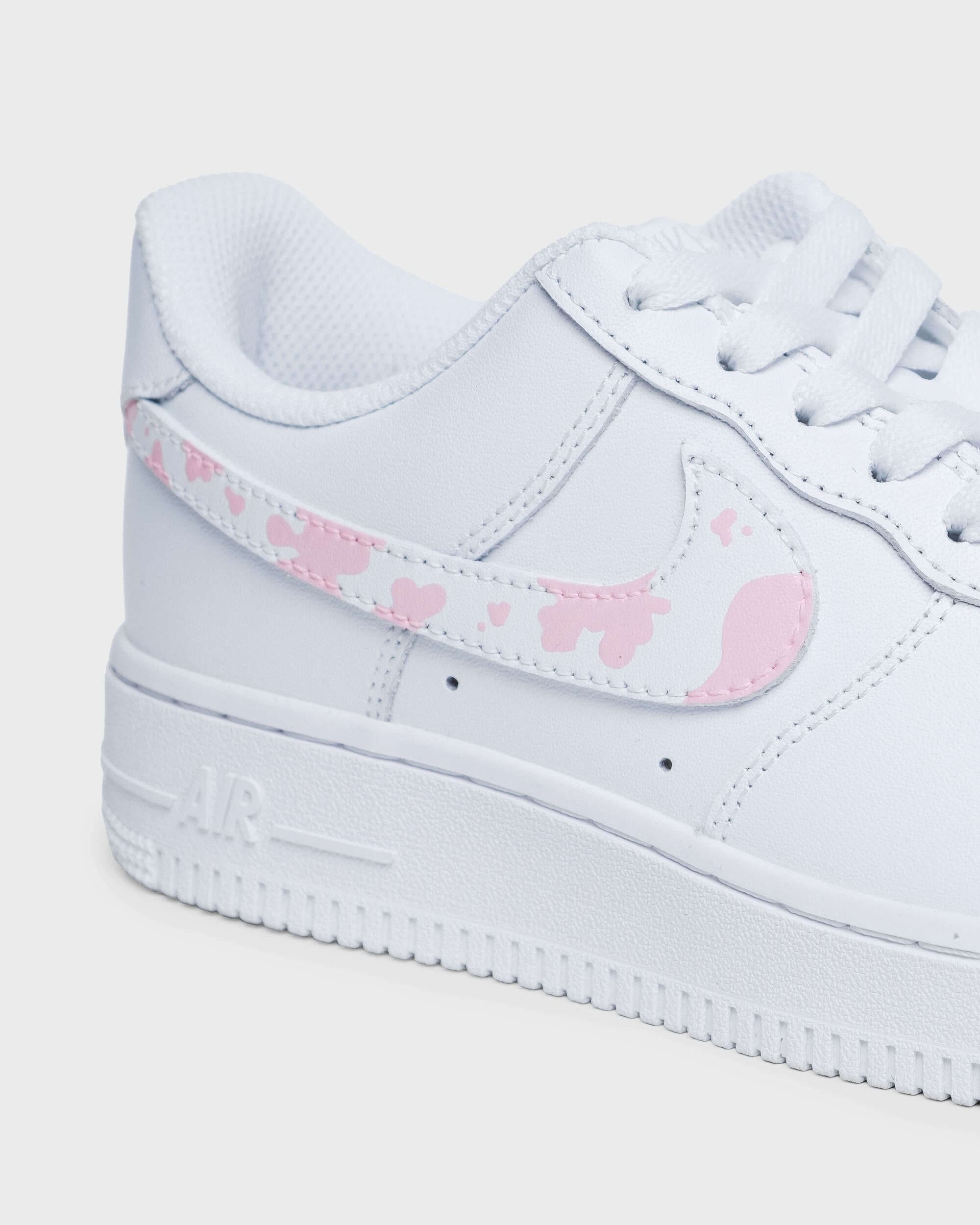Close-up of custom pink cow print design on Nike Air Force 1 sneaker swoosh.