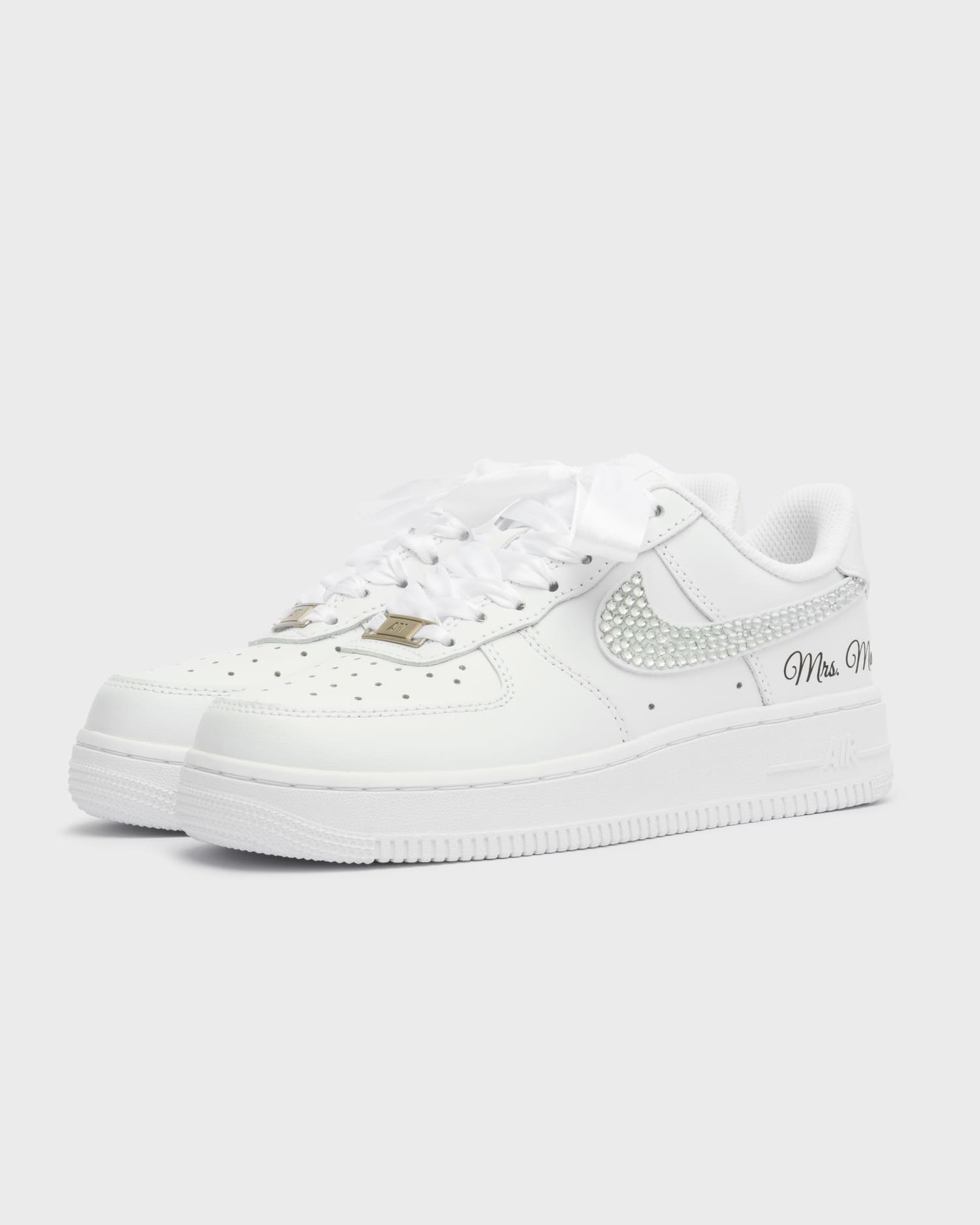 Custom white Air Force 1 wedding sneakers with shimmering rhinestone swoosh. Handcrafted bridal shoes with satin laces and personalized embroidery 'Mrs. Maur'. Elegant and stylish custom wedding footwear.