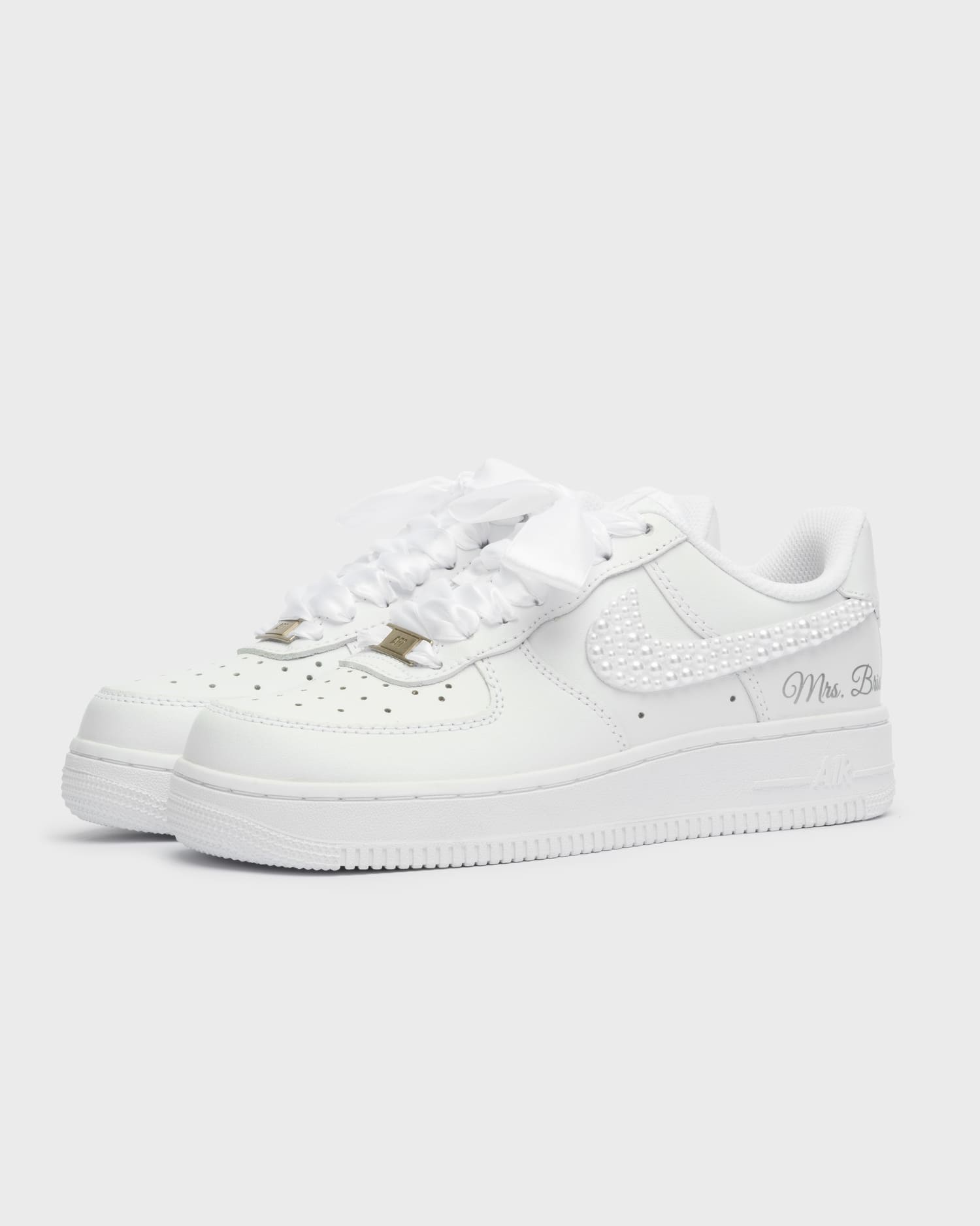 Custom white Air Force 1 wedding sneakers with pearl-embellished swoosh. Handcrafted bridal shoes with satin laces and personalized 'Mrs. Bride' embroidery. Elegant and stylish wedding sneakers for brides.
