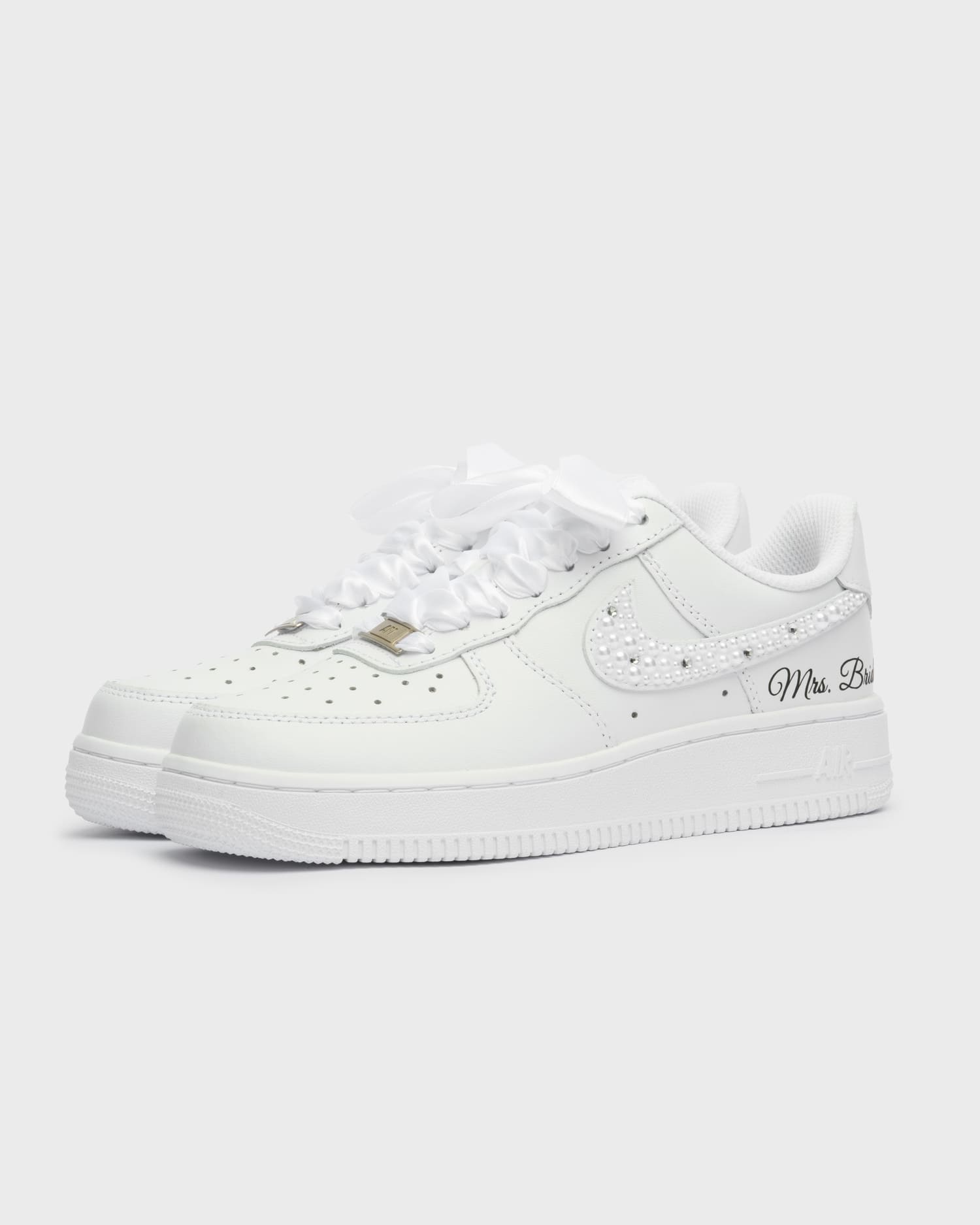 Custom white Air Force 1 wedding sneakers with pearl-embellished swoosh. Handcrafted bridal shoes with satin laces and personalized 'Mrs. Bride' embroidery. Elegant and unique wedding footwear.