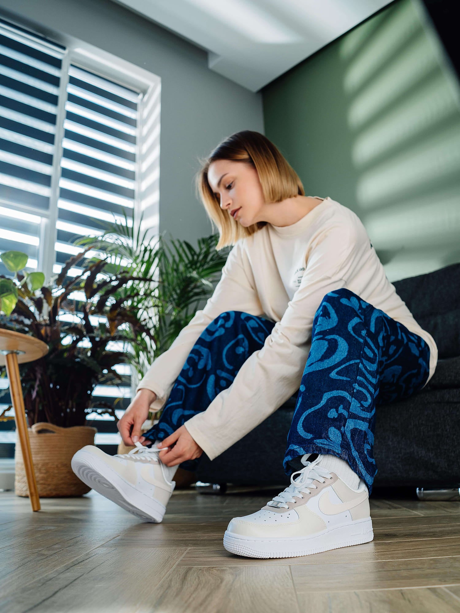 Model adjusting custom beige Air Force 1 sneakers with minimalist hand-painted details, ideal for fans of neutral, personalized footwear.