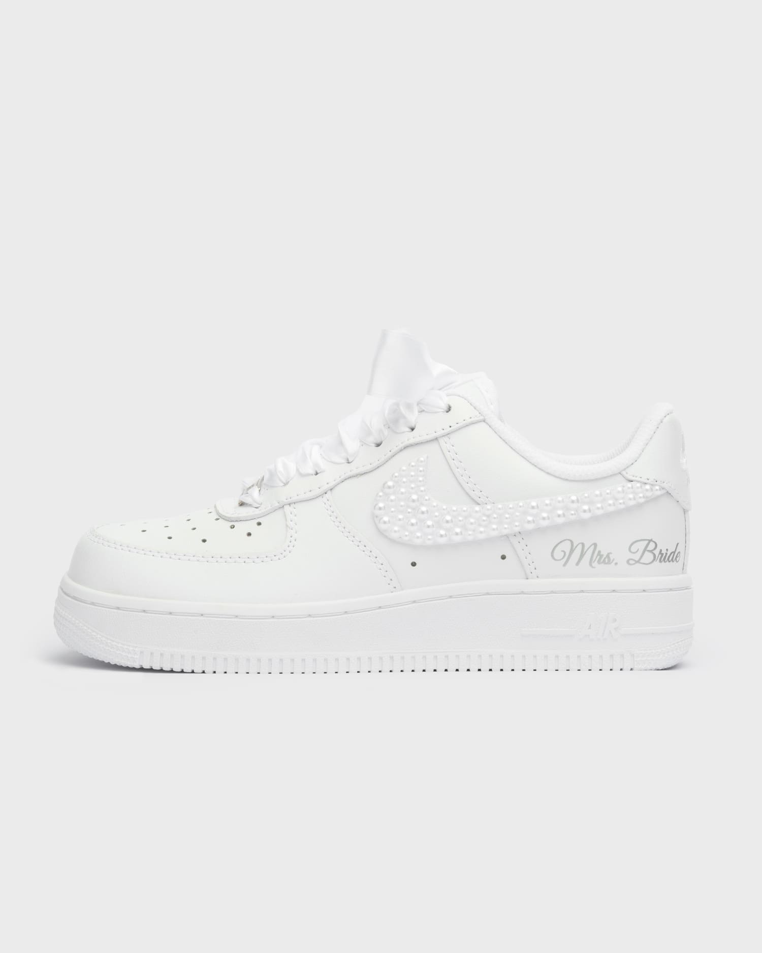 White Air Force 1 custom bridal sneakers with pearl details on the swoosh. Personalized wedding shoes with 'Mrs. Bride' embroidery and satin laces, perfect for a unique bridal look.