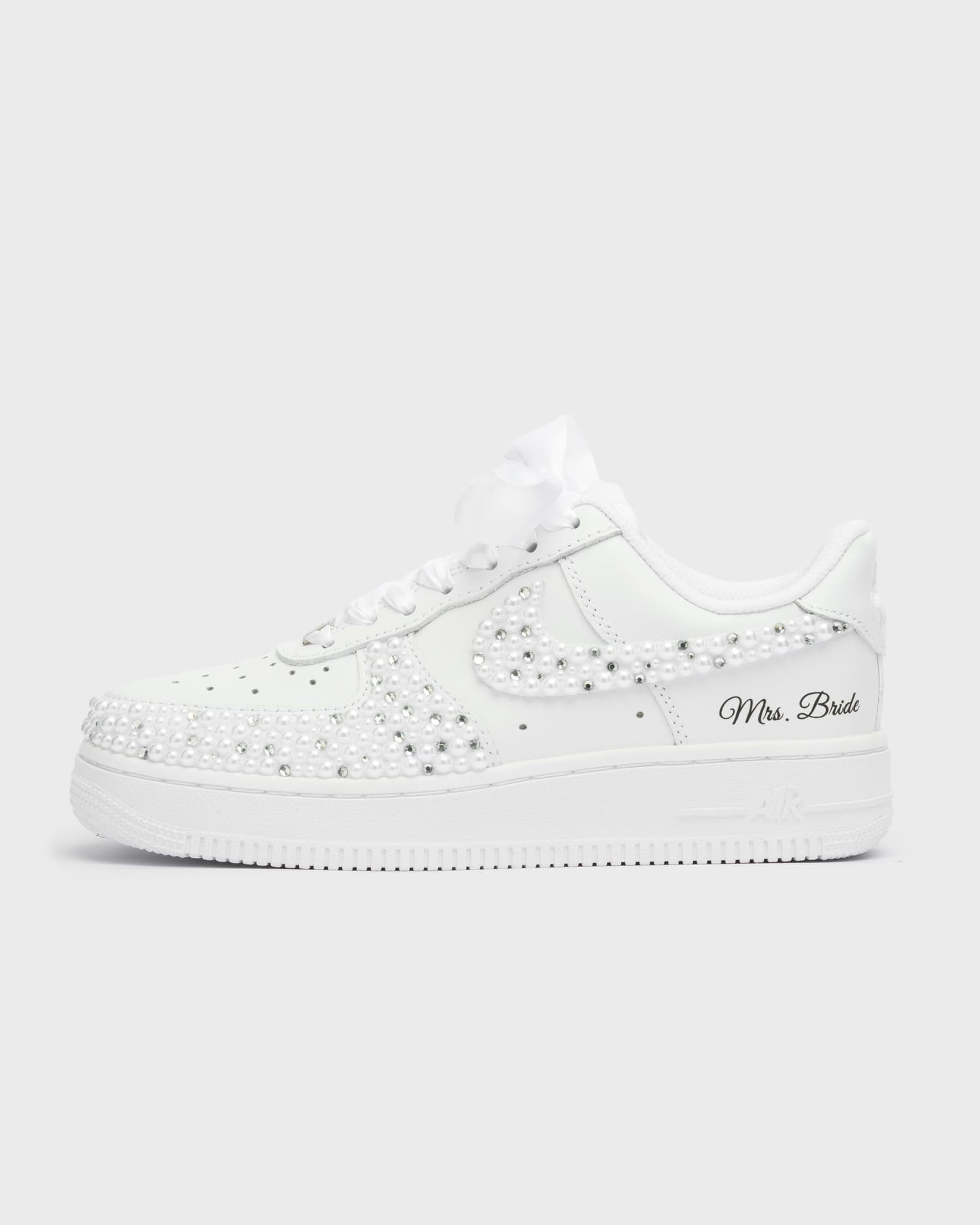 White Air Force 1 custom bridal sneakers covered in pearls on the swoosh and toe box. Personalized wedding shoes with 'Mrs. Bride' embroidery and satin laces, perfect for a luxurious bridal look.
