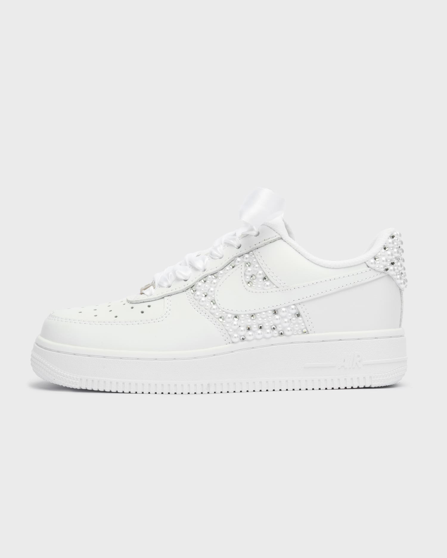 Custom white Air Force 1 wedding sneakers with pearl embellishments on the swoosh and heel. Handcrafted personalized bridal shoes with satin laces, perfect for a unique wedding look. Elegant and stylish custom Nike sneakers for brides.
