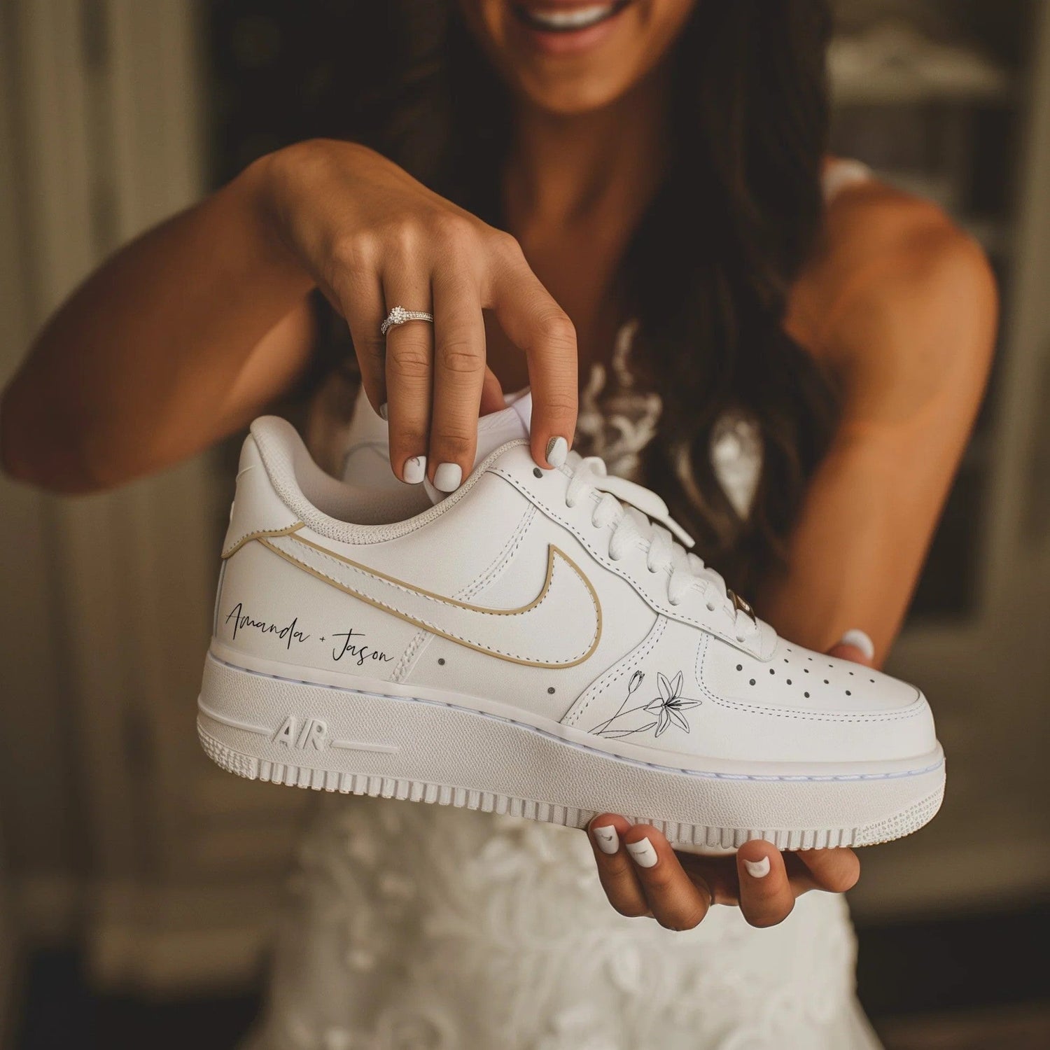 Bride holding customized wedding sneakers air force 1 with personalization, featuring a delicate gold outline on the logo and a subtle floral design, showcasing her engagement ring.