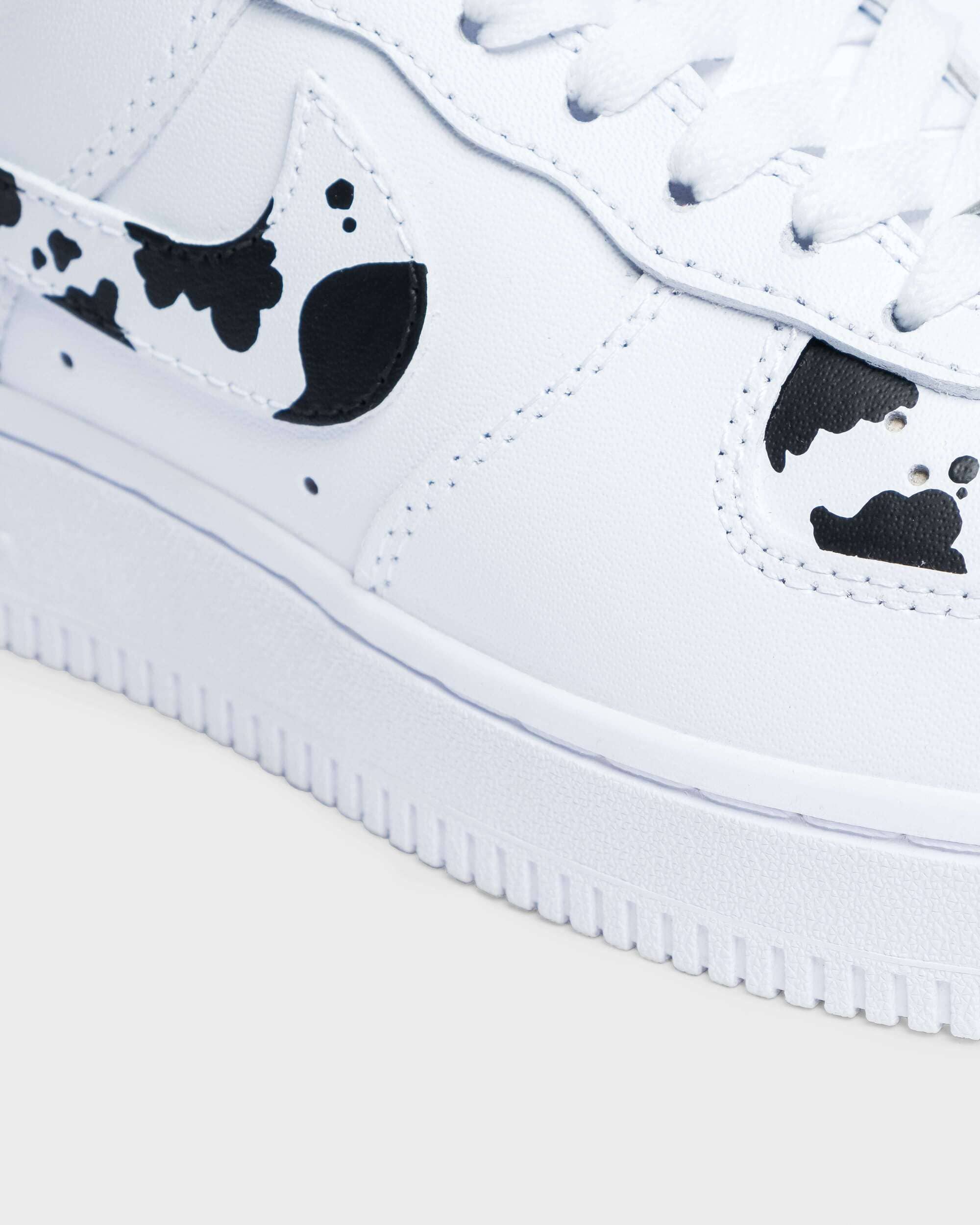 Close-up of custom Air Force 1 sneaker with hand-painted black cow print pattern, adding a unique and personalized touch. 