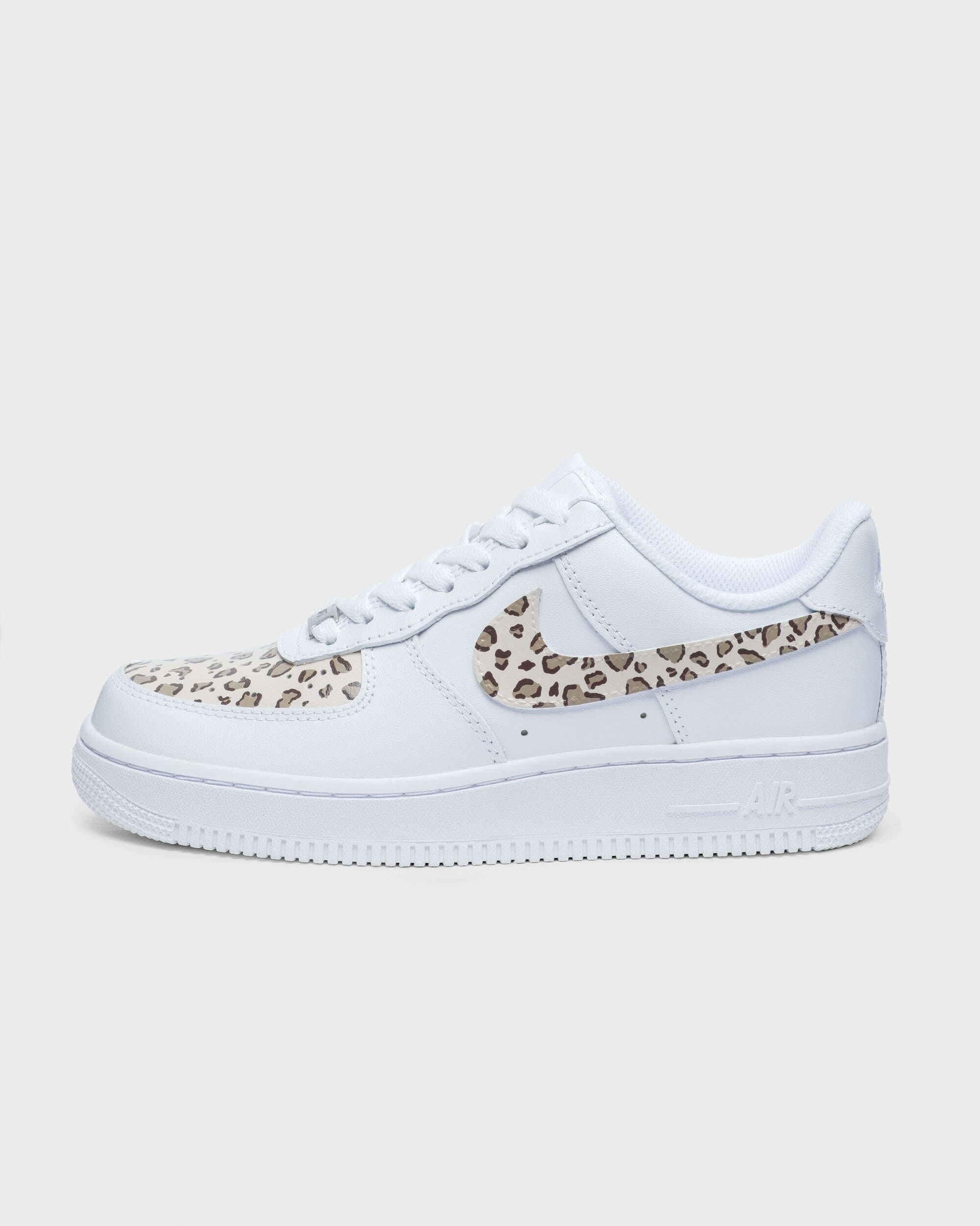 Side profile of custom Air Force 1 sneaker with leopard print swoosh and accents on white leather, perfect for a bold, fashionable statement.