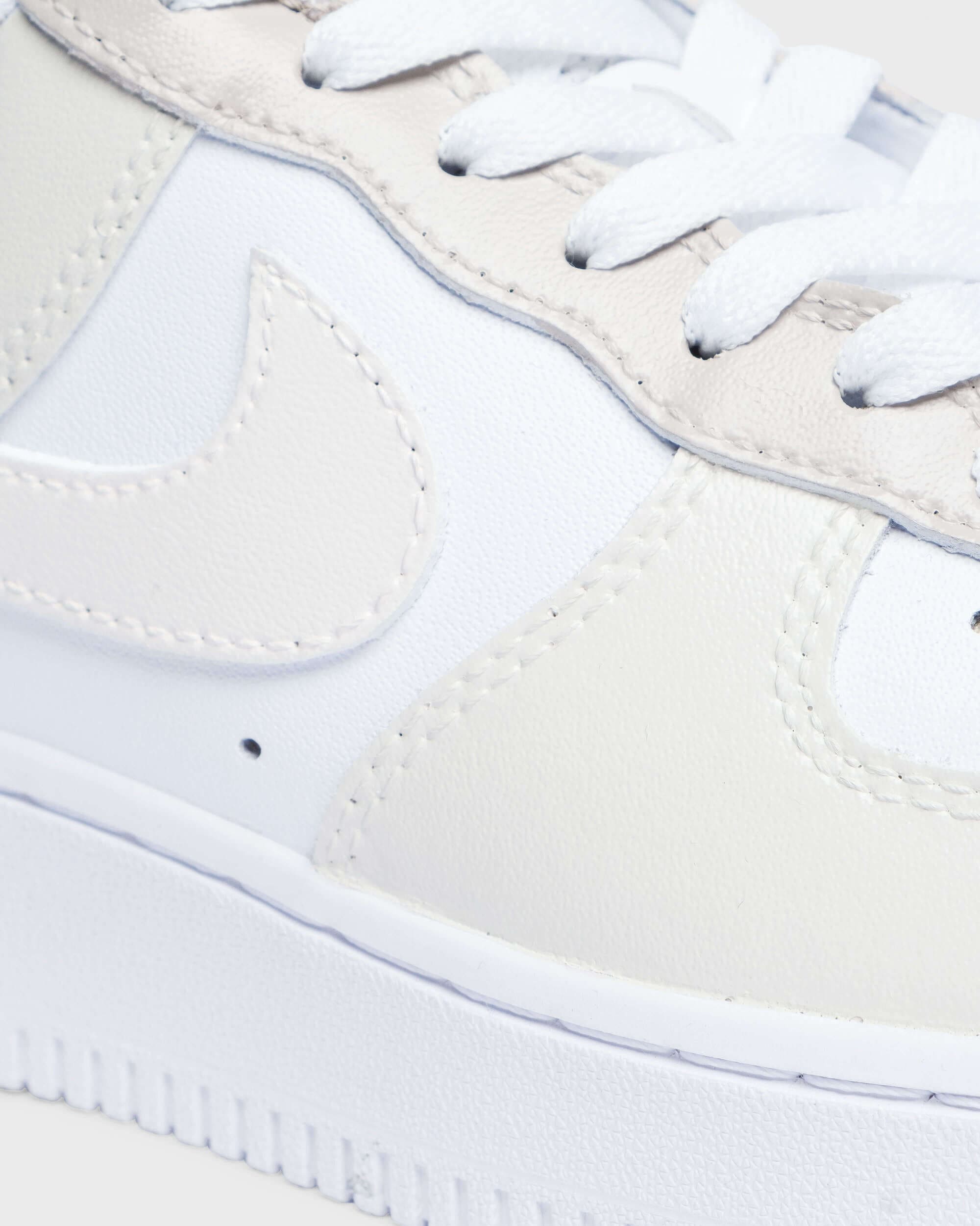 Close-up of custom beige and white Air Force 1 sneakers with a soft-toned swoosh, showcasing minimalistic hand-painted details. Ideal for personalized style seekers.