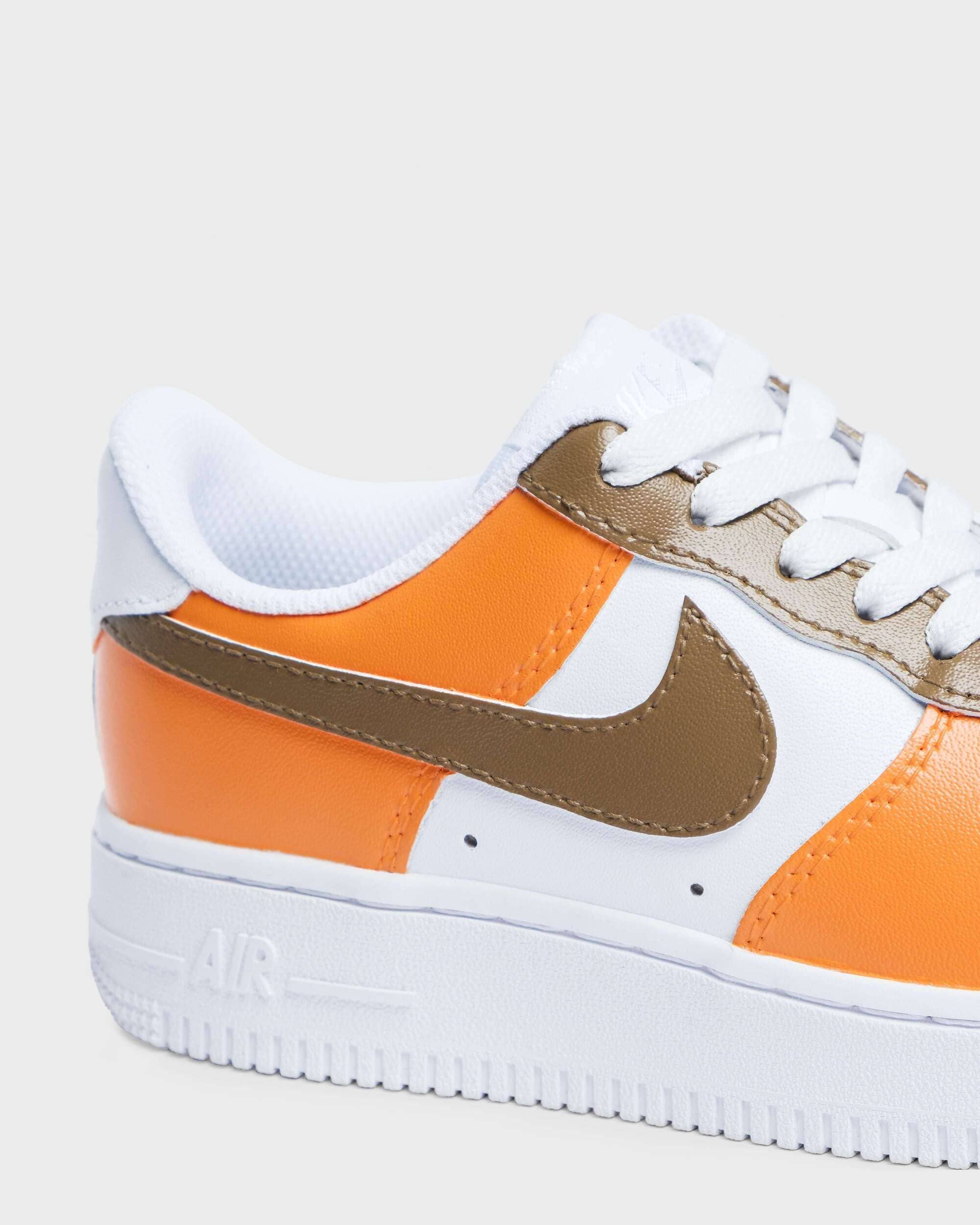 Close-up of custom Air Force 1 sneaker with vibrant orange overlays and a brown swoosh on a white leather base, showcasing a bold and stylish color combination.