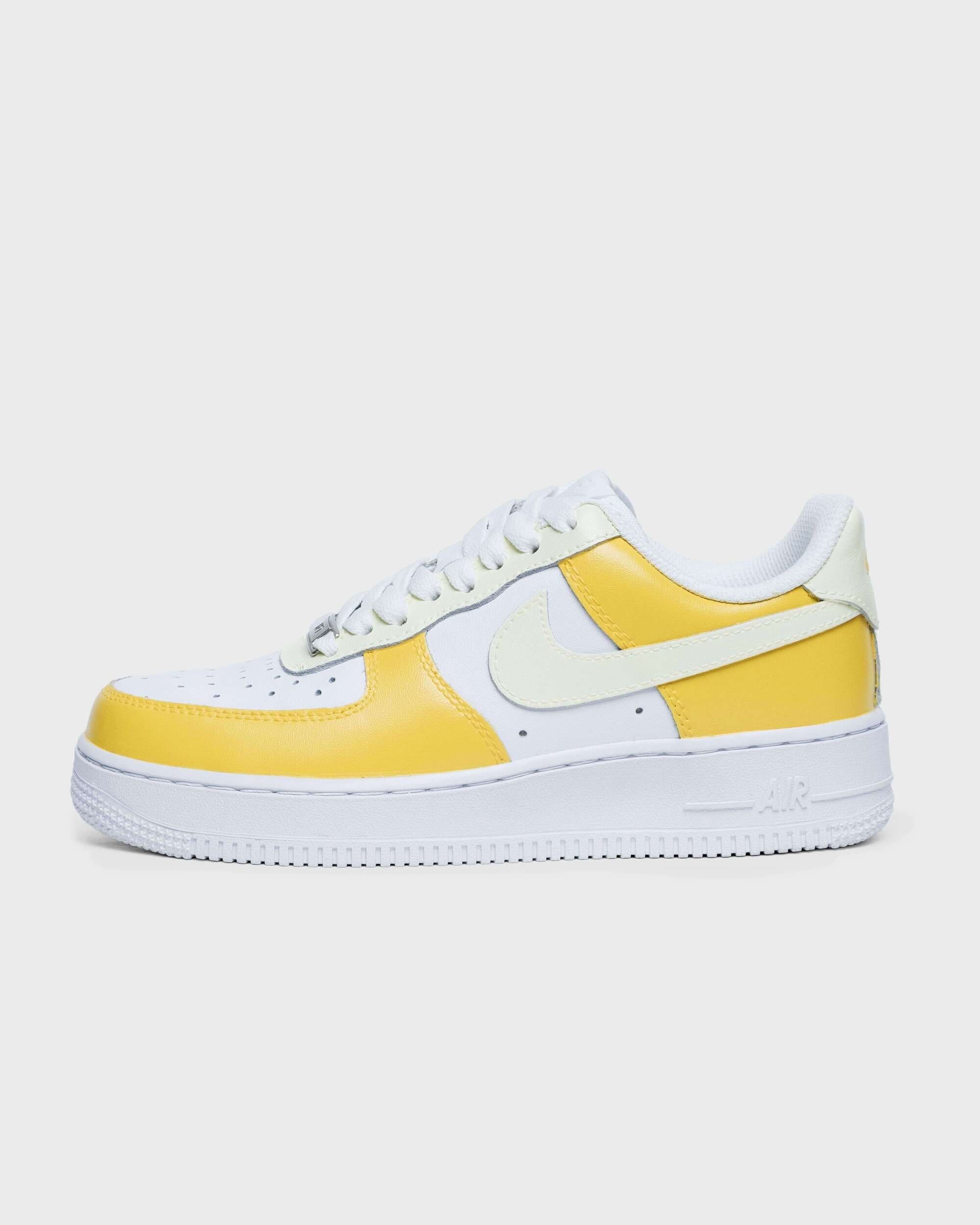 Side view of single sneaker: Yellow and white custom Air Force 1 sneaker, side view, highlighting the distinctive design and Nike logo.