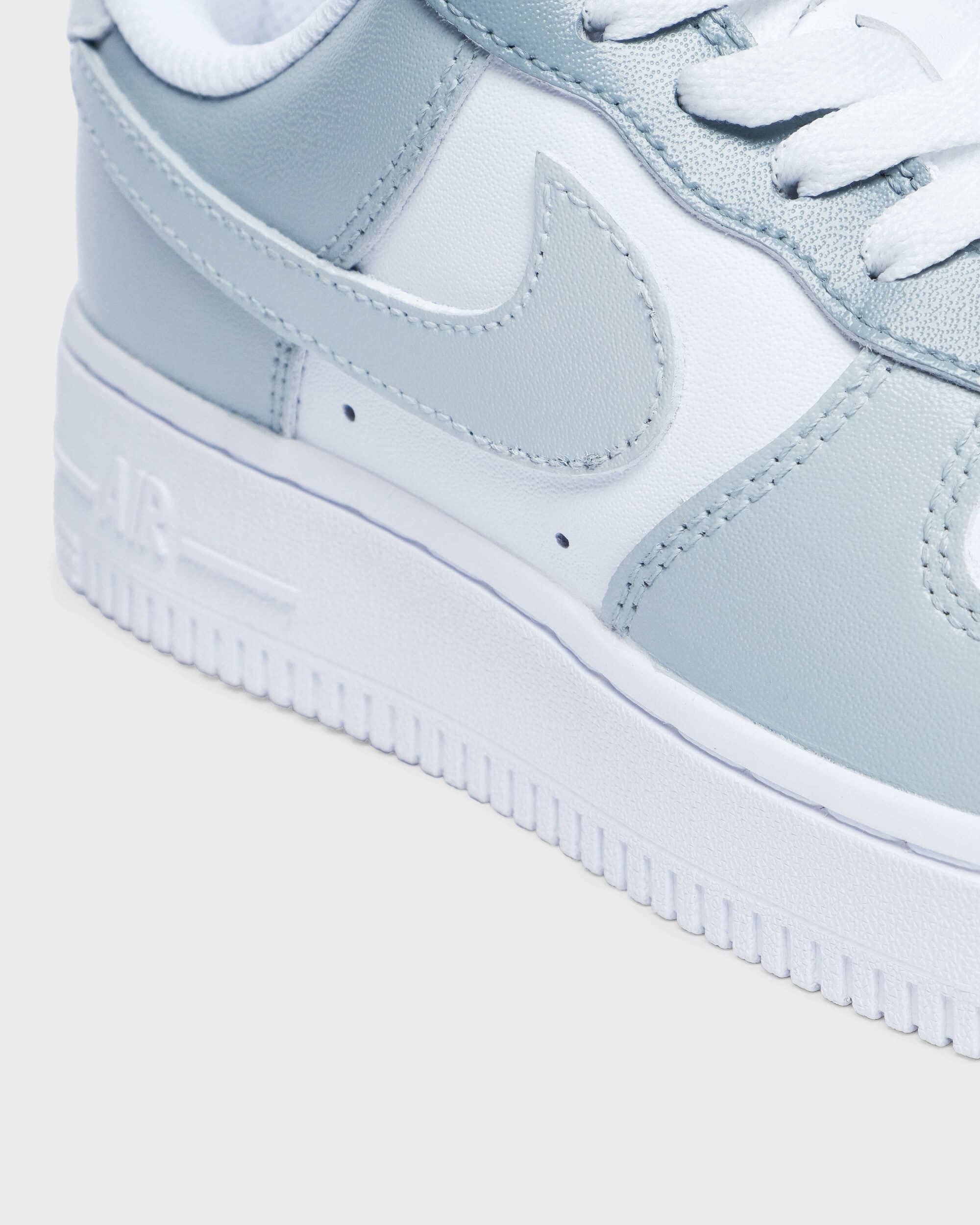 Close-up of custom Air Force 1 sneaker with light gray overlays on a white leather base, showcasing the detailed stitching and minimalist design for a unique, personalized look.