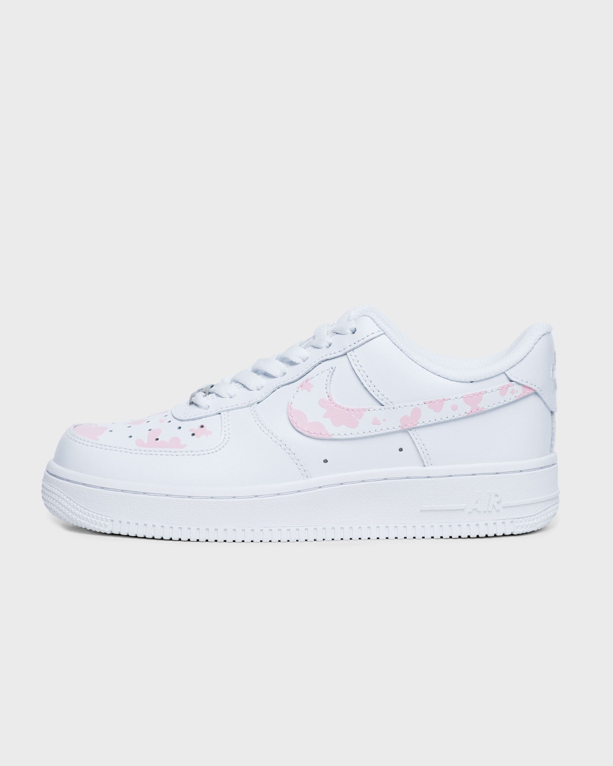 Side profile of custom Nike Air Force 1 sneaker with pink cow print design.