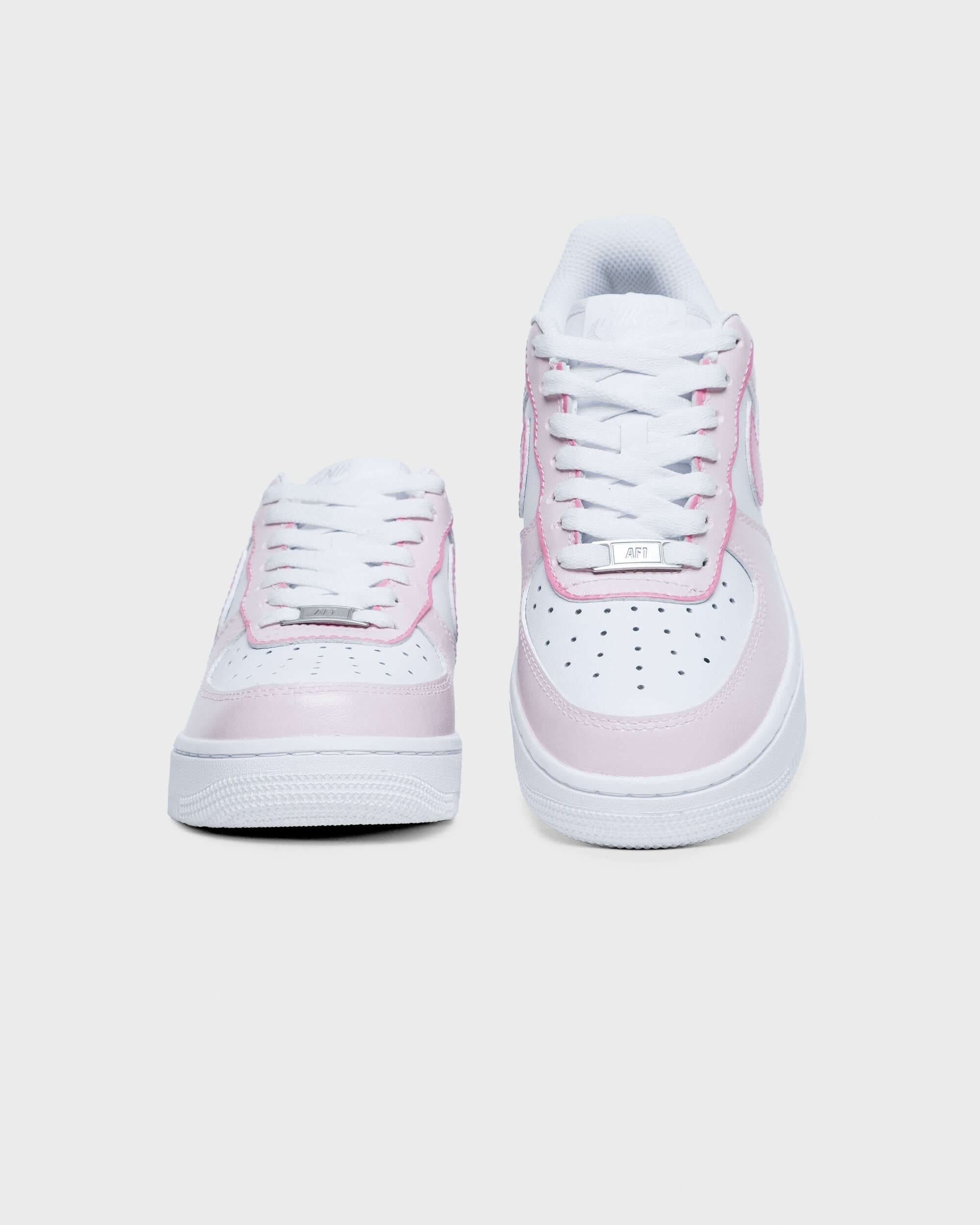 Front view of custom Air Force 1 sneakers with pink accents, displaying the laces and perforated toe box for a stylish look.