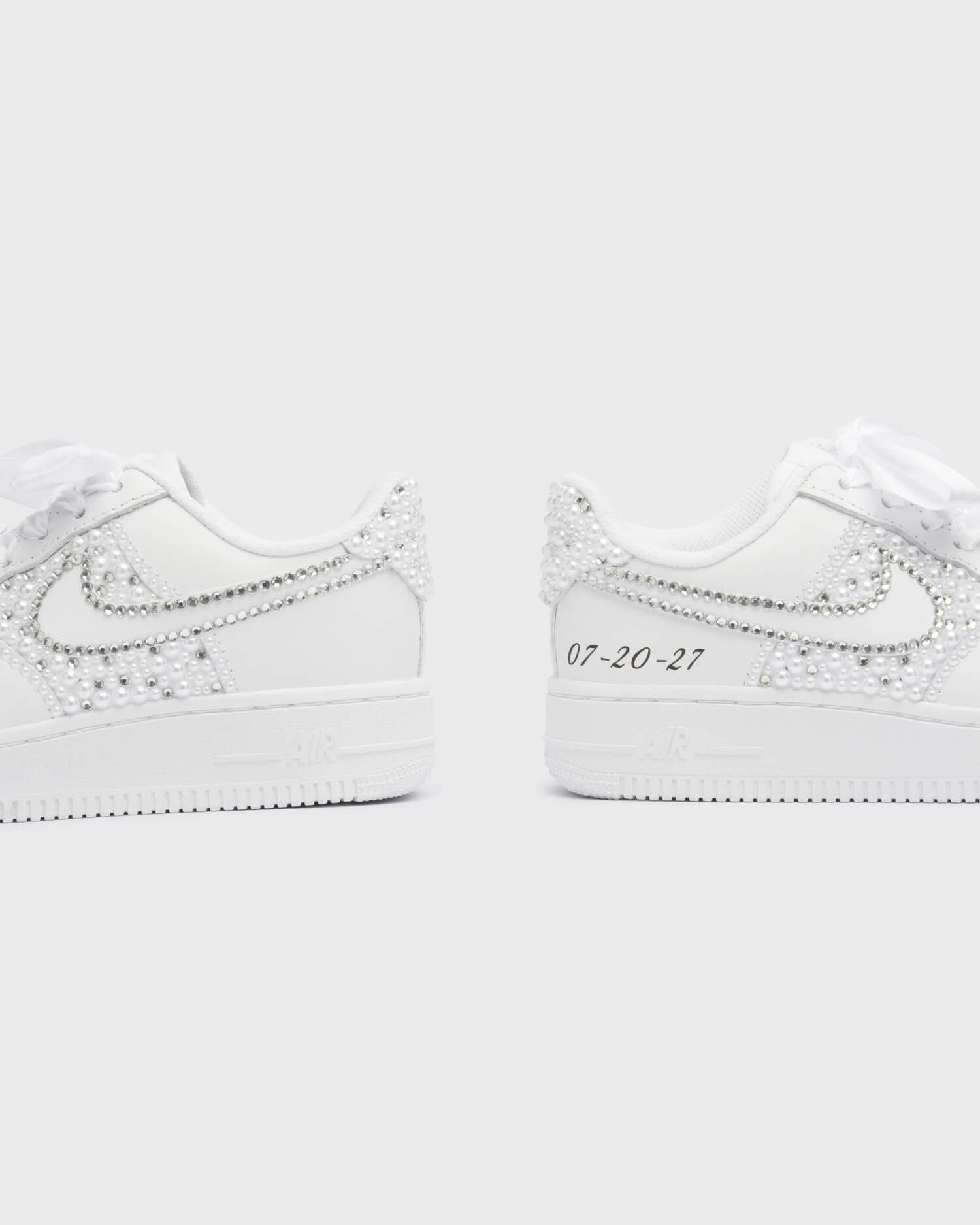 Custom white Air Force 1 bridal sneakers with pearl and rhinestone heel design and personalized wedding date engraving.