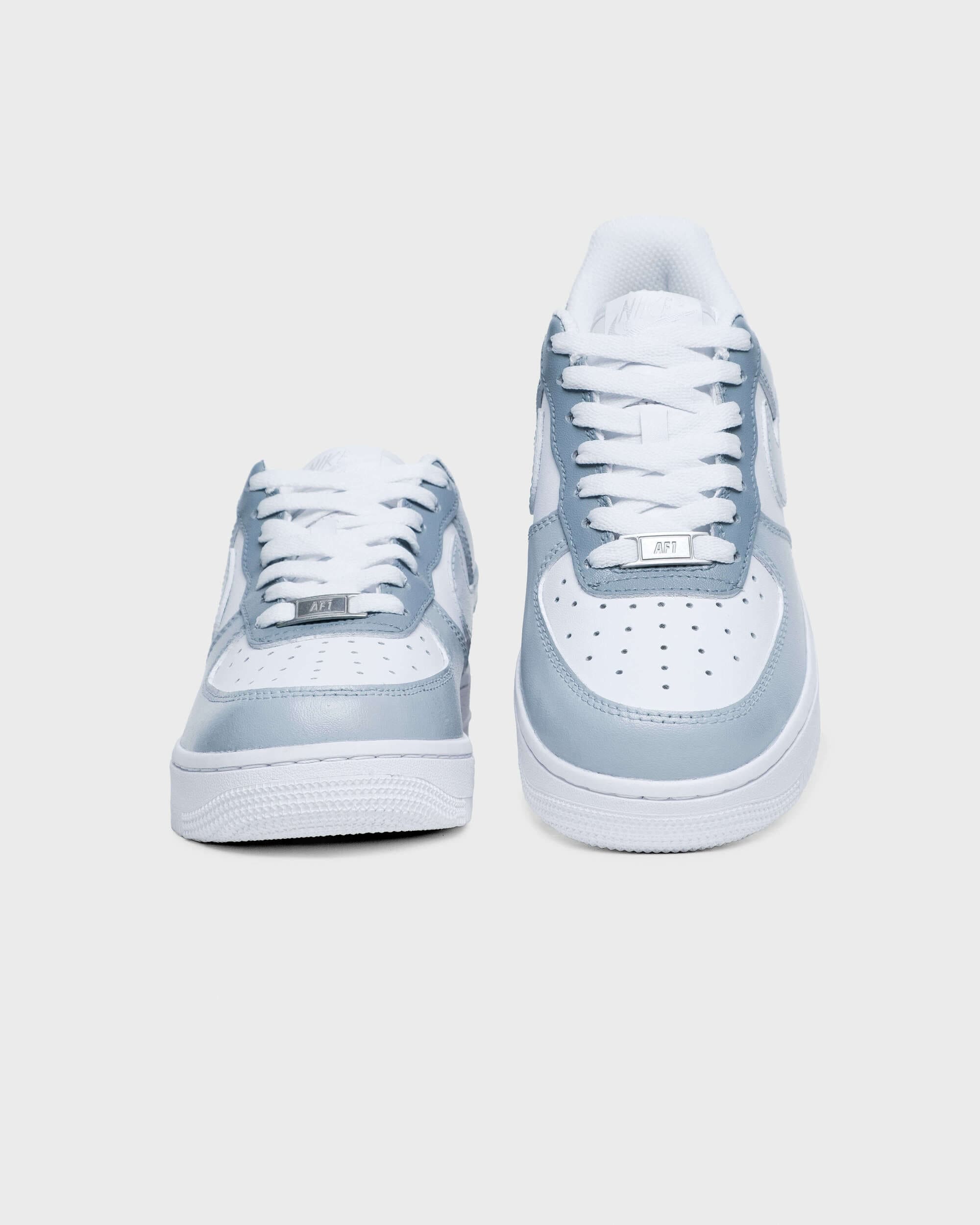 Front view of custom Air Force 1 sneakers with light gray accents, white laces, and perforated toe box, emphasizing a clean, contemporary style.
