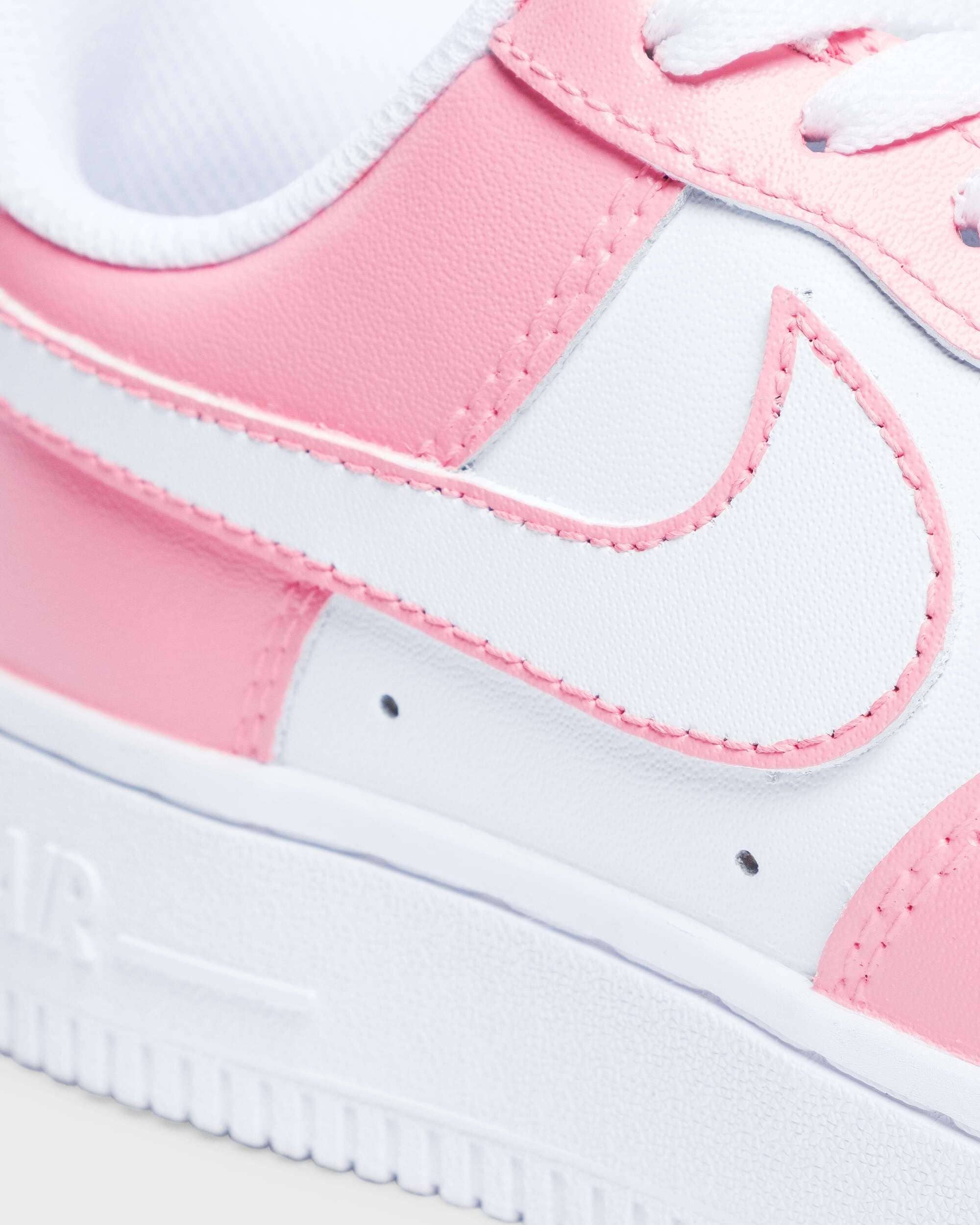 Close-up of pink and white custom Air Force 1 sneakers – emphasizing the custom pink detailing on a classic Nike Air Force 1 shoe.