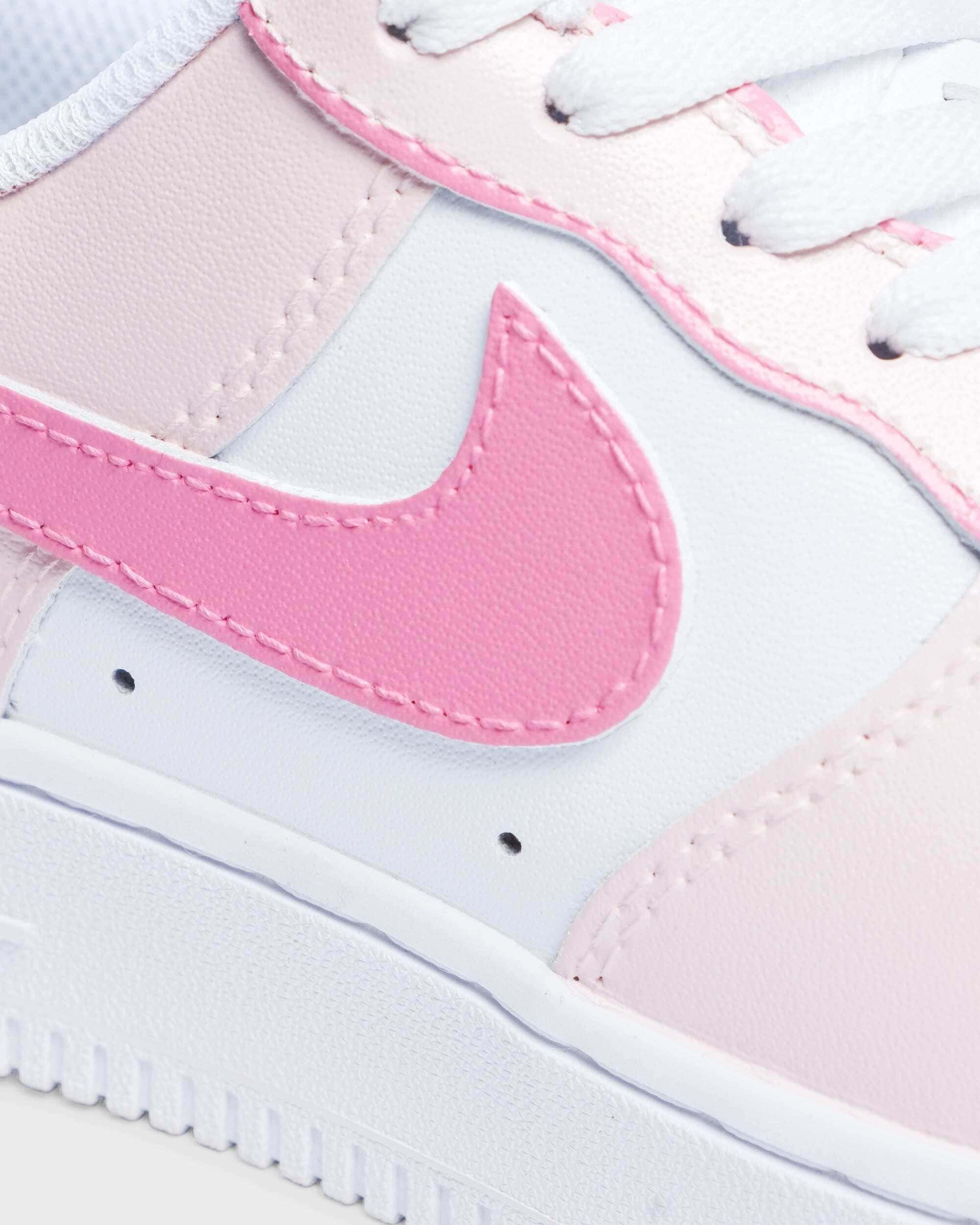 Close-up view of custom Air Force 1 sneaker with pink details, highlighting the pink swoosh logo and pastel color accents.