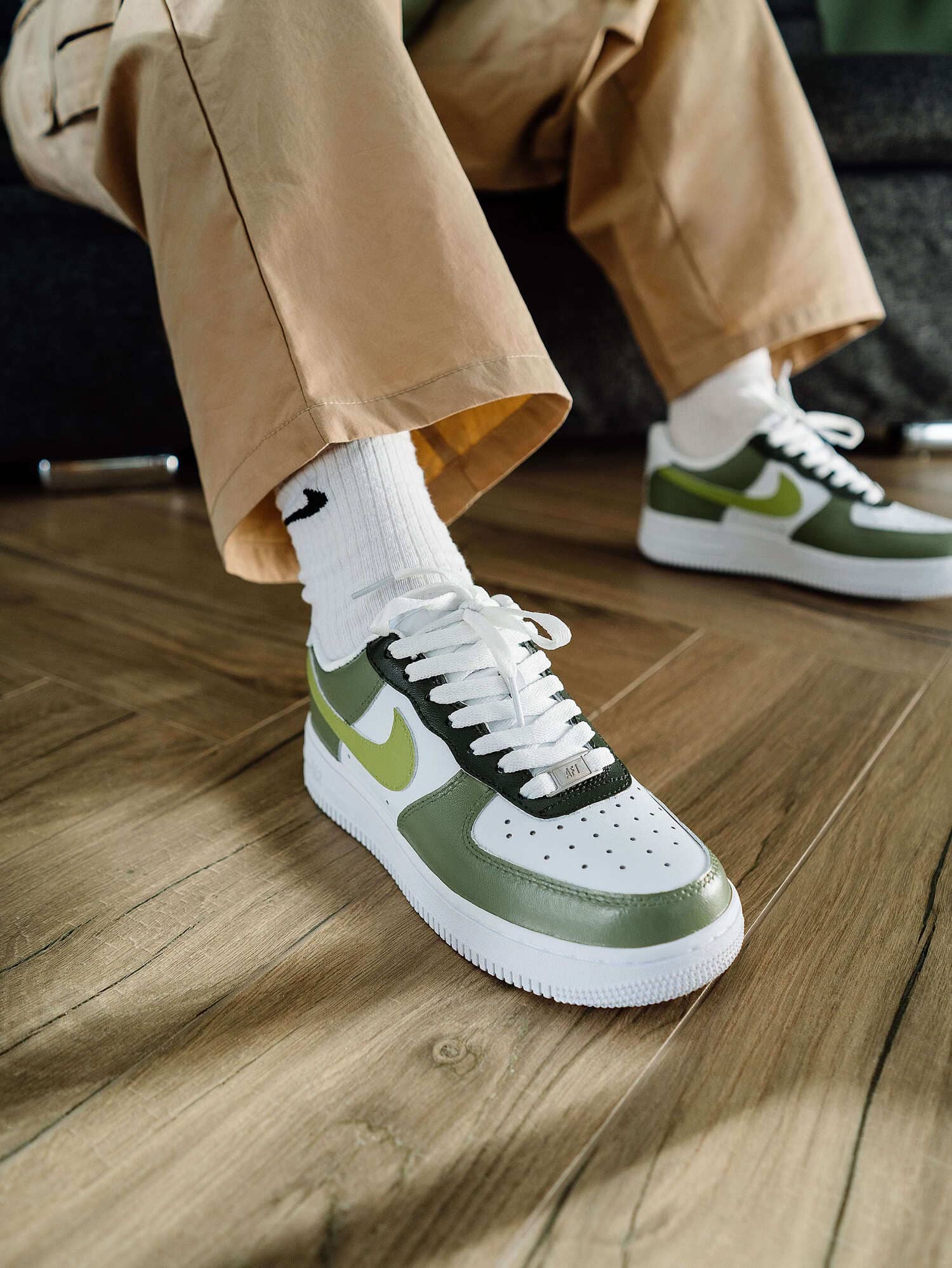 Close-up of Nike Air Force 1 sneaker in green with lime swoosh, worn by person in white Nike socks.