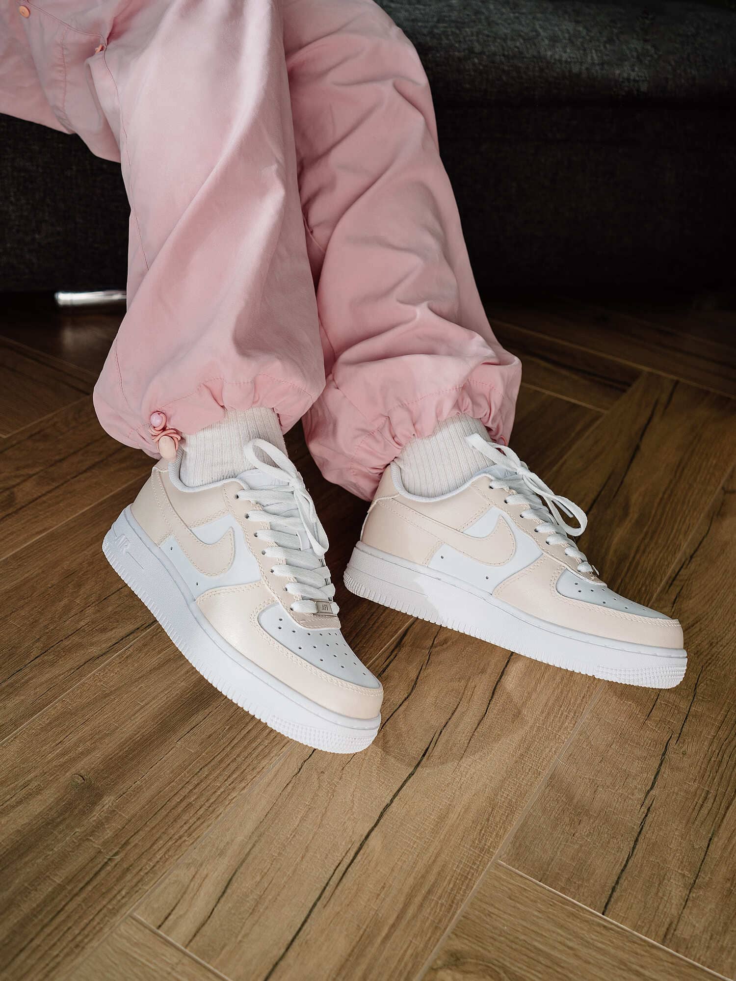 Close-up of cream-colored custom Air Force 1 sneakers on model, showcasing a clean and modern look.