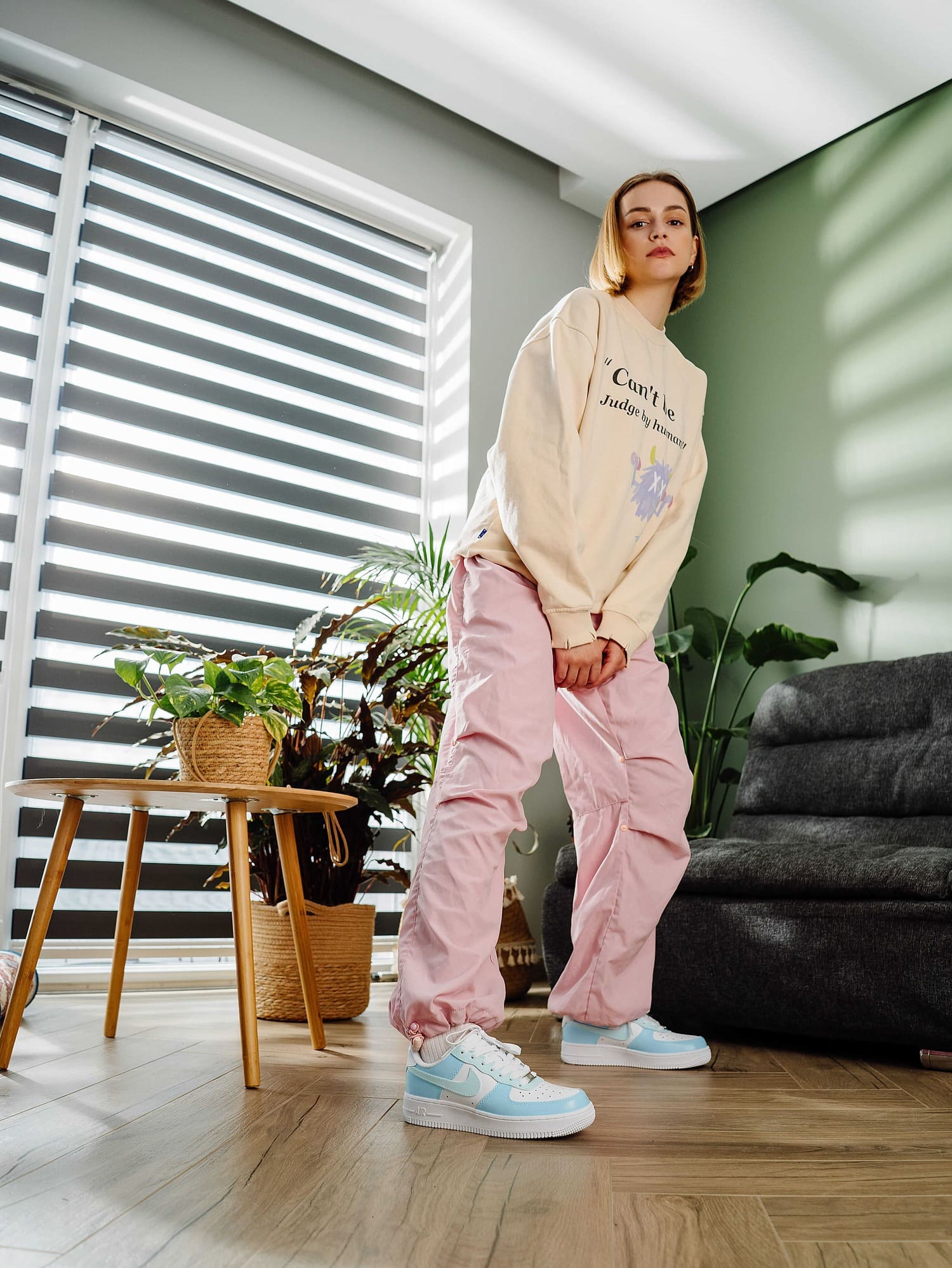 Model wearing custom Air Force 1 sneakers with light blue overlays, styled with pink pants, creating a vibrant and personalized look.