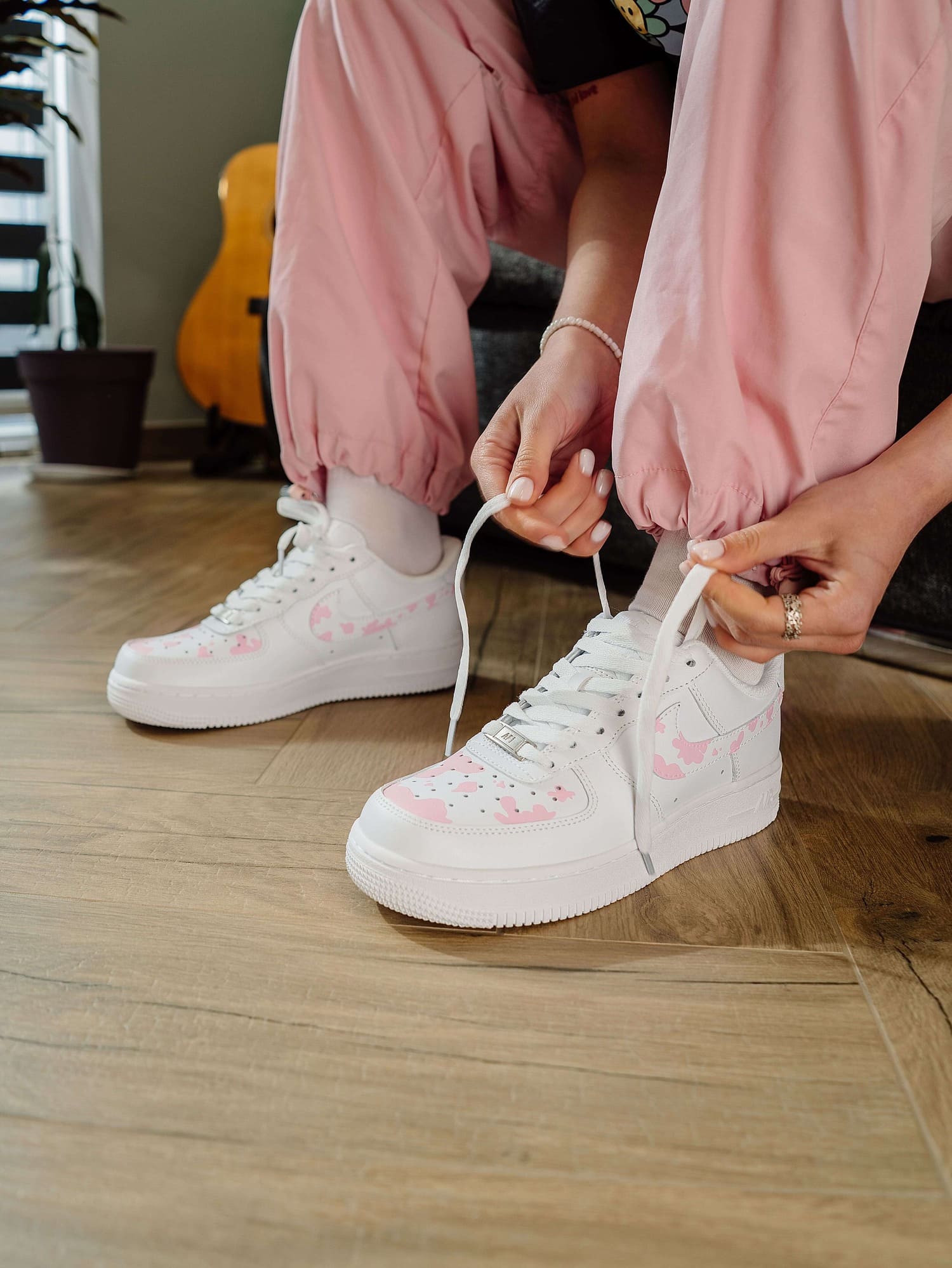 Detailed view of pink cow print Air Force 1 custom sneakers, tying the laces.