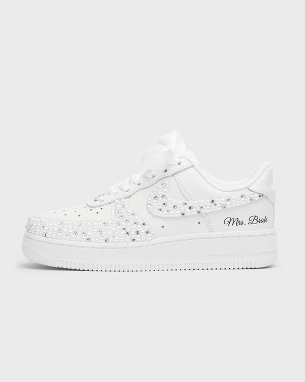 White Air Force 1 custom bridal sneakers covered in pearls on the swoosh and toe box. Personalized wedding shoes with 'Mrs. Bride' embroidery and satin laces, perfect for a luxurious bridal look.